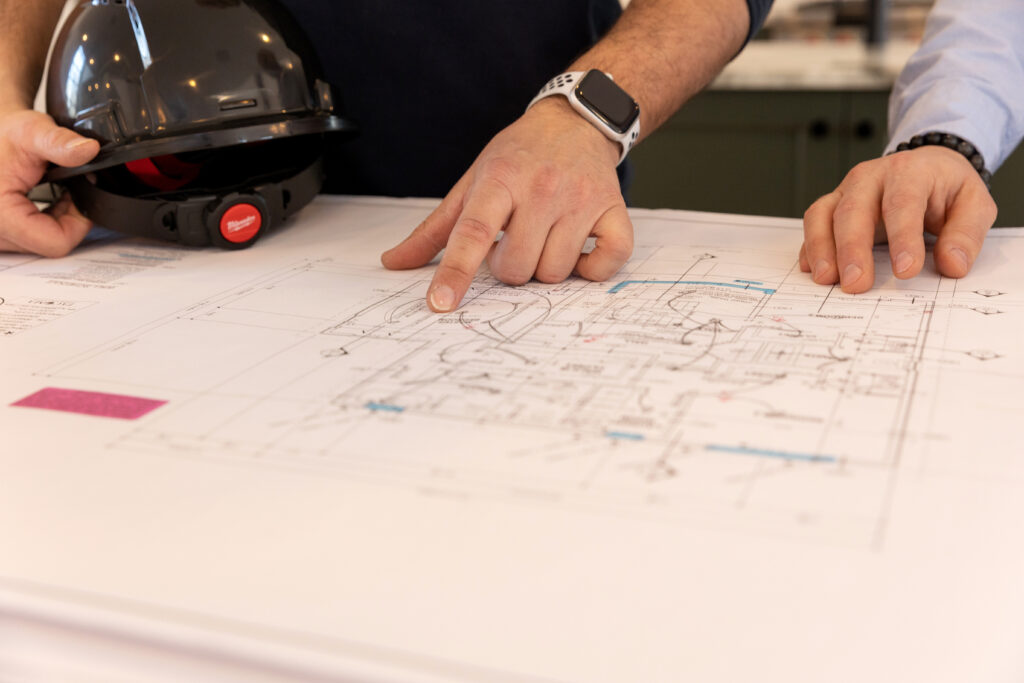Two people reviewing architectural drawings on a desk as part of the property development and custom home planning process.
